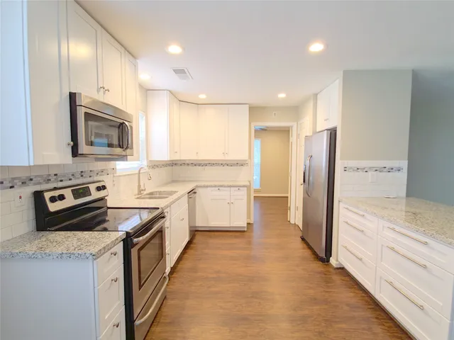 a kitchen with stainless steel appliances granite countertop a refrigerator a stove top oven a sink and dishwasher