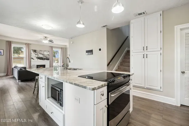 a kitchen with kitchen island granite countertop a sink cabinets and wooden floor