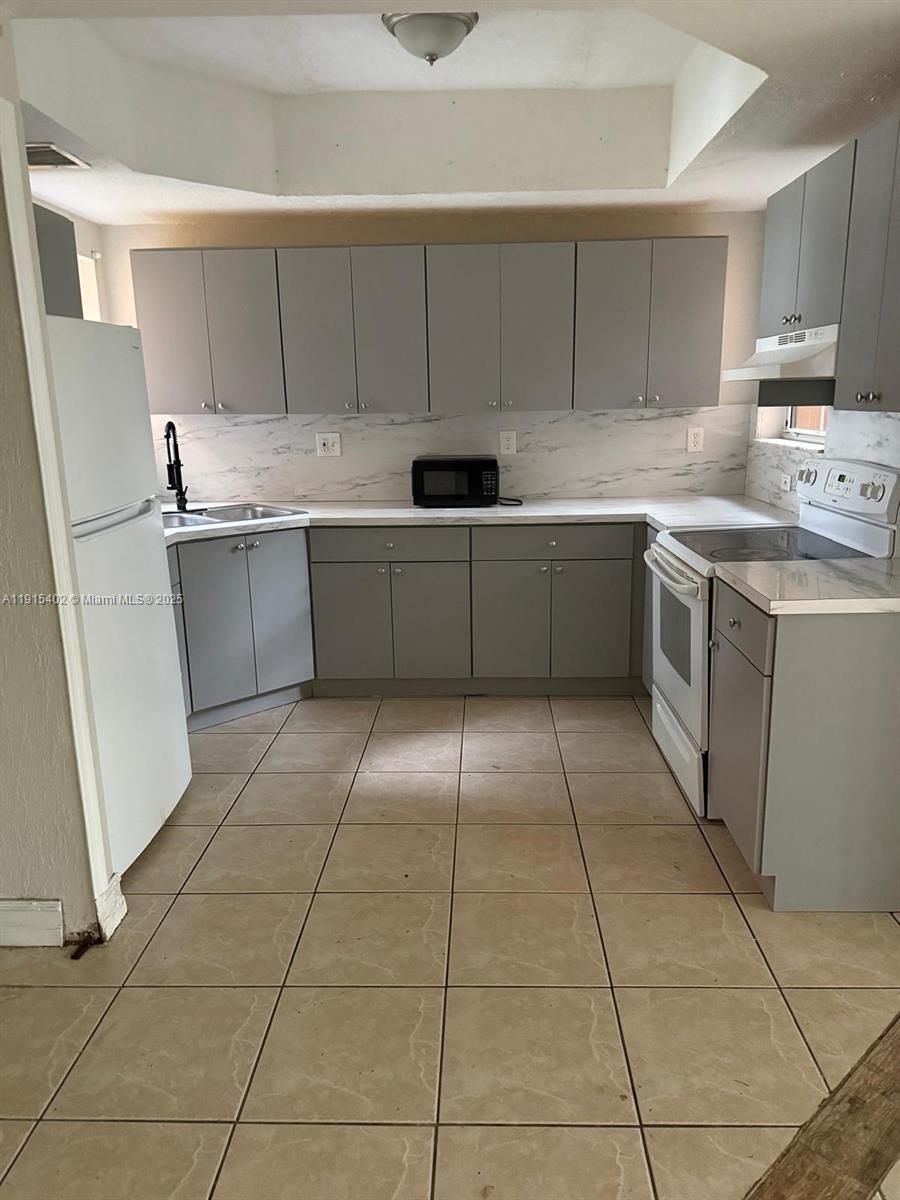 657 Southwest 10th Street, Unit 657 Florida City, FL 33034 - Photo 10 of 12 a kitchen with a sink a stove top oven and cabinets