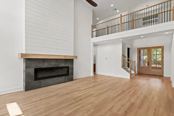a view of an empty room with wooden floor fireplace and a window