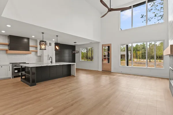 a living room with stainless steel appliances kitchen island wooden cabinets and a fireplace