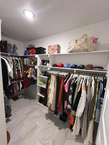 a view of walk in closet with clothes and shoes