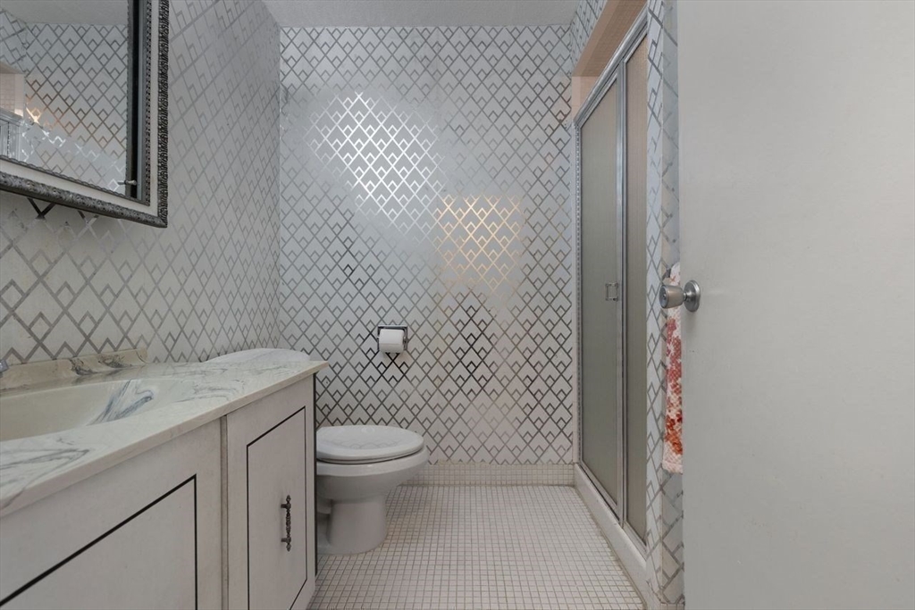 1008 Paradise Road, Unit 2Q Swampscott, MA 01907 - Photo 18 of 25 a bathroom with a granite countertop toilet a sink and a shower