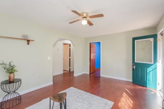 a view of an empty room with wooden floor and a ceiling fan