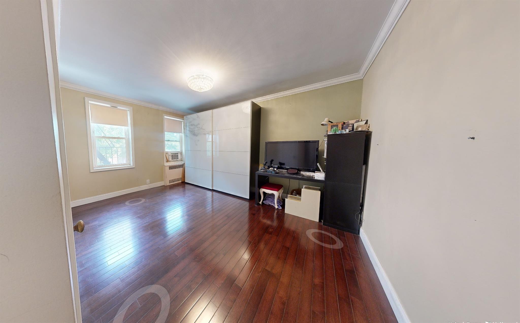 94-10 64th Road, Unit B6 Queens, NY 11374 - Photo 14 of 17 Unfurnished living room with crown molding, dark wood-style flooring, baseboards, and radiator heating unit