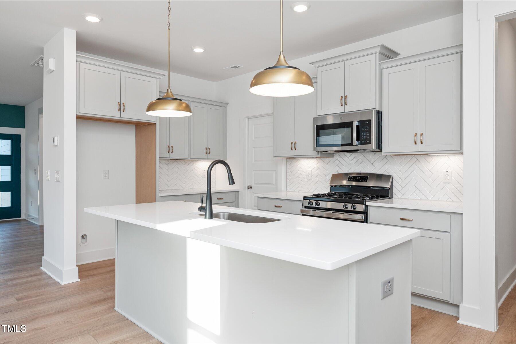 3939 Willow Gate Way Raleigh, NC 27604 - Photo 11 of 32 a kitchen with stainless steel appliances a stove a sink a microwave and cabinets