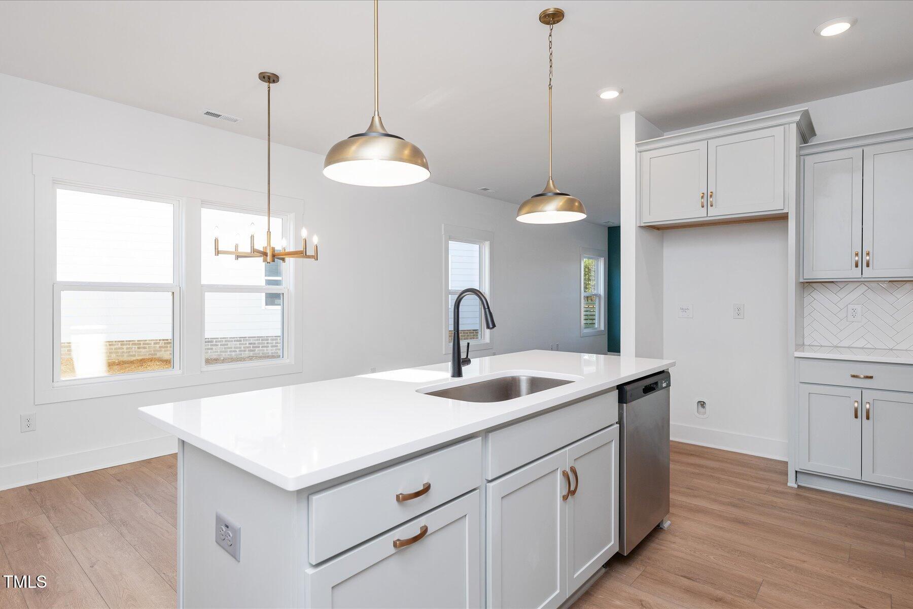 3939 Willow Gate Way Raleigh, NC 27604 - Photo 12 of 32 a kitchen with a sink chandelier and wooden floor