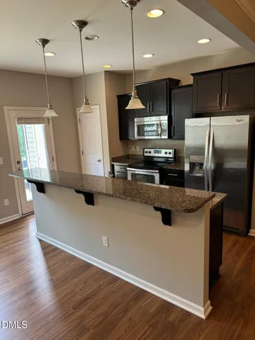 a kitchen with stainless steel appliances granite countertop a refrigerator a sink a stove and a wooden floors