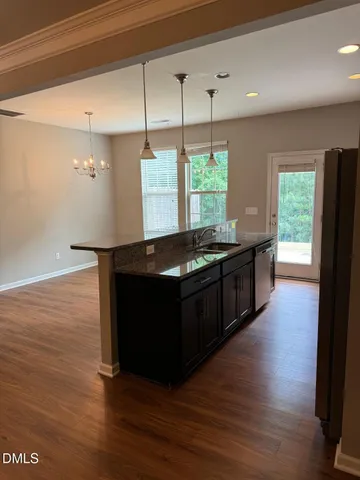 a kitchen with stainless steel appliances granite countertop a sink a stove and a wooden floor