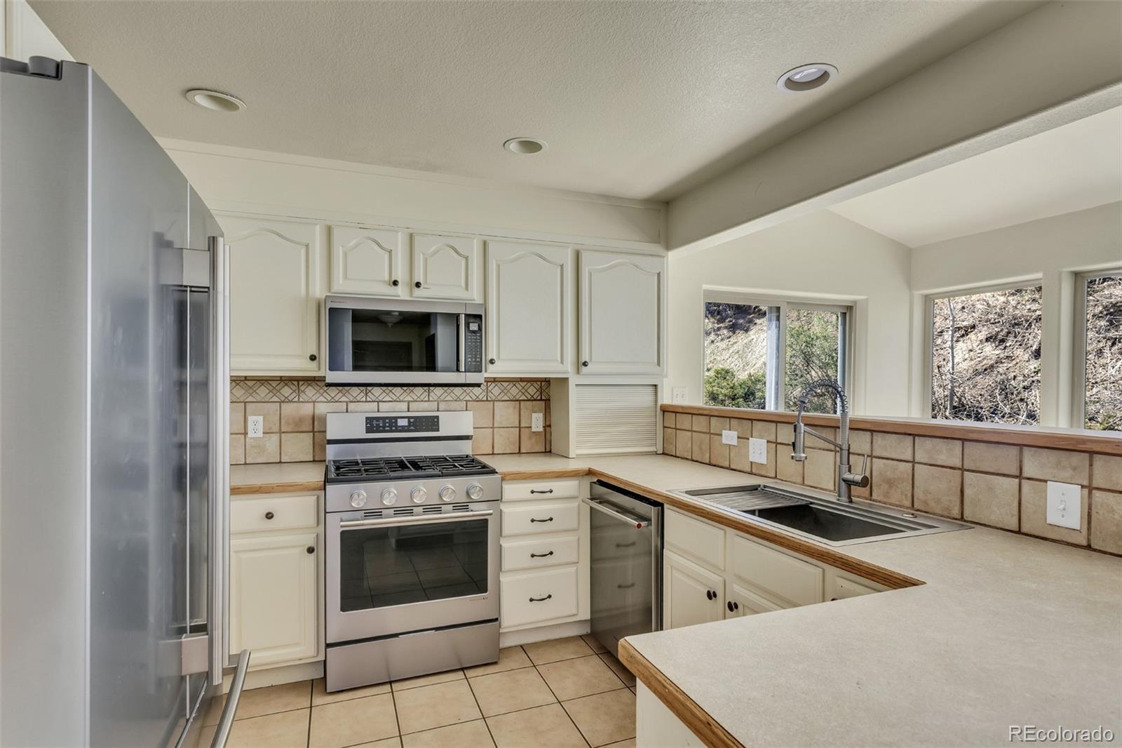 12183 Arnett Ranch Road Littleton, CO 80127 - Photo 8 of 28 a kitchen with white cabinets and stainless steel appliances