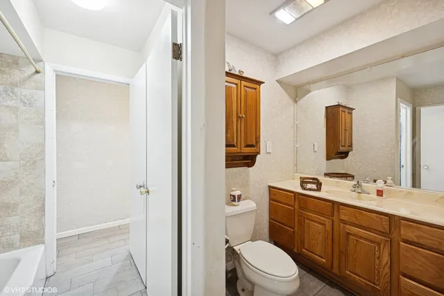 a bathroom with a toilet a sink a mirror a vanity and shower