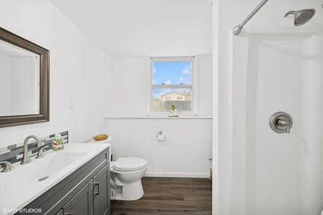a bathroom with a granite countertop toilet a sink and mirror