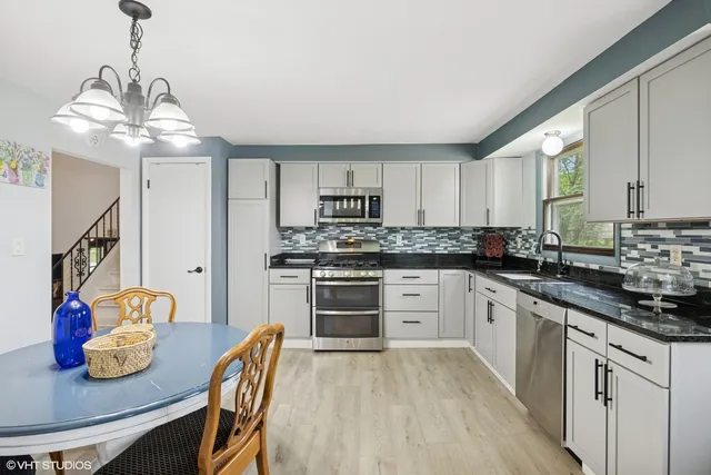 a kitchen with stainless steel appliances granite countertop a stove top oven a sink dishwasher and white cabinets