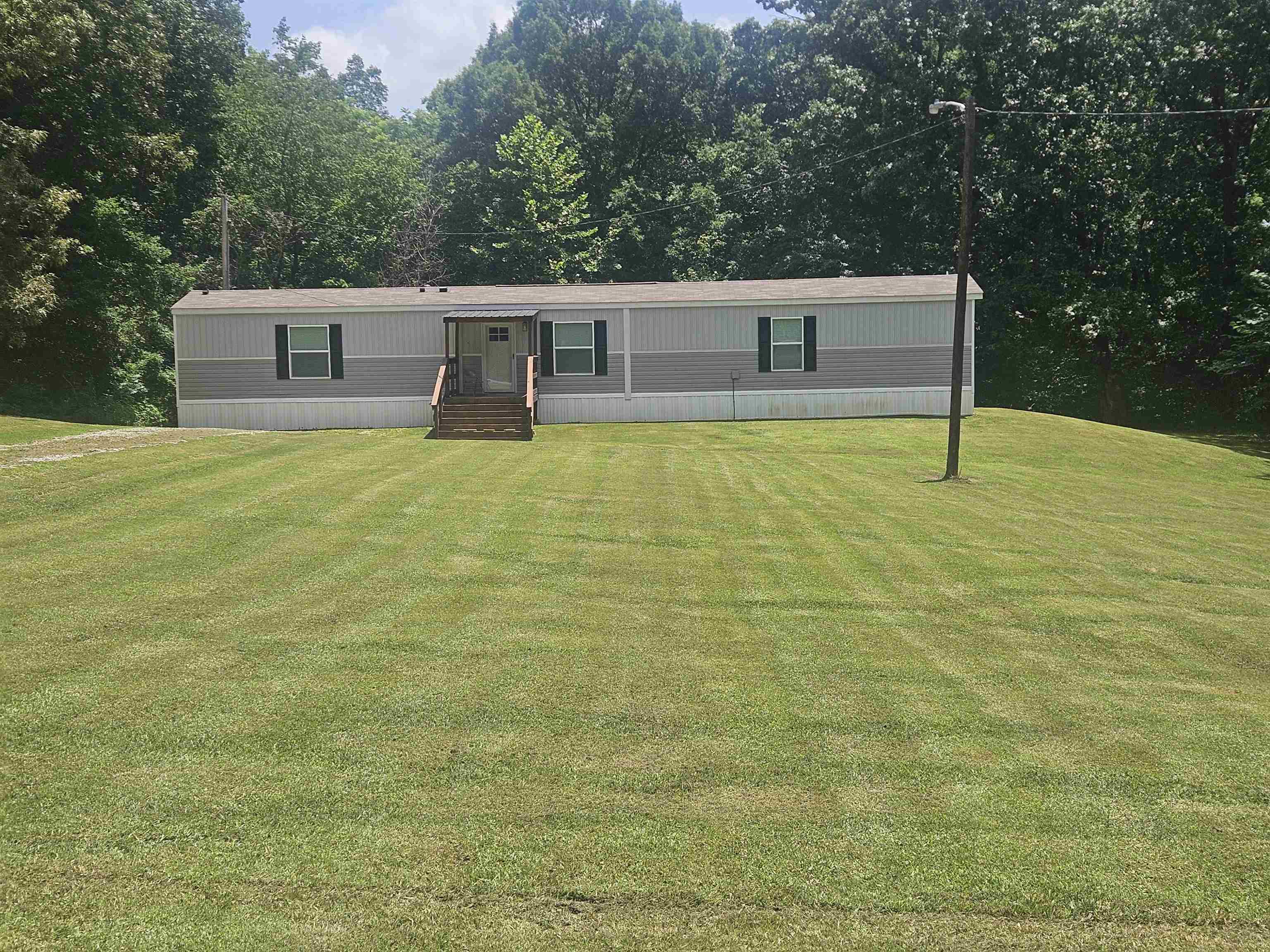 75 Pittman Road, Unit ROAD Somerville, TN 38068 - Photo 1 of 26 Residential structure featuring horizontal siding, a covered porch with wood stairs and railing, and dark window shutters