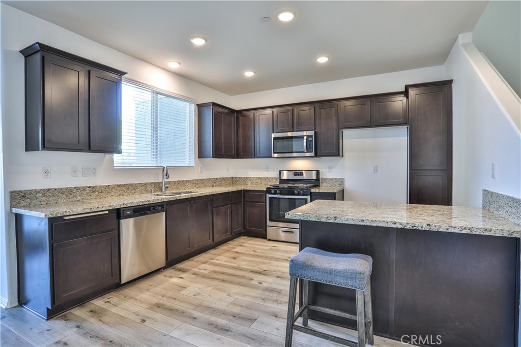 7863 Marbil Lane Riverside, CA 92504 - Photo 9 of 30 a kitchen with kitchen island granite countertop a sink cabinets and stainless steel appliances