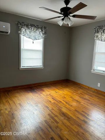 an empty room with a windows and chandelier fan
