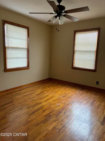 an empty room with a window and a ceiling fan