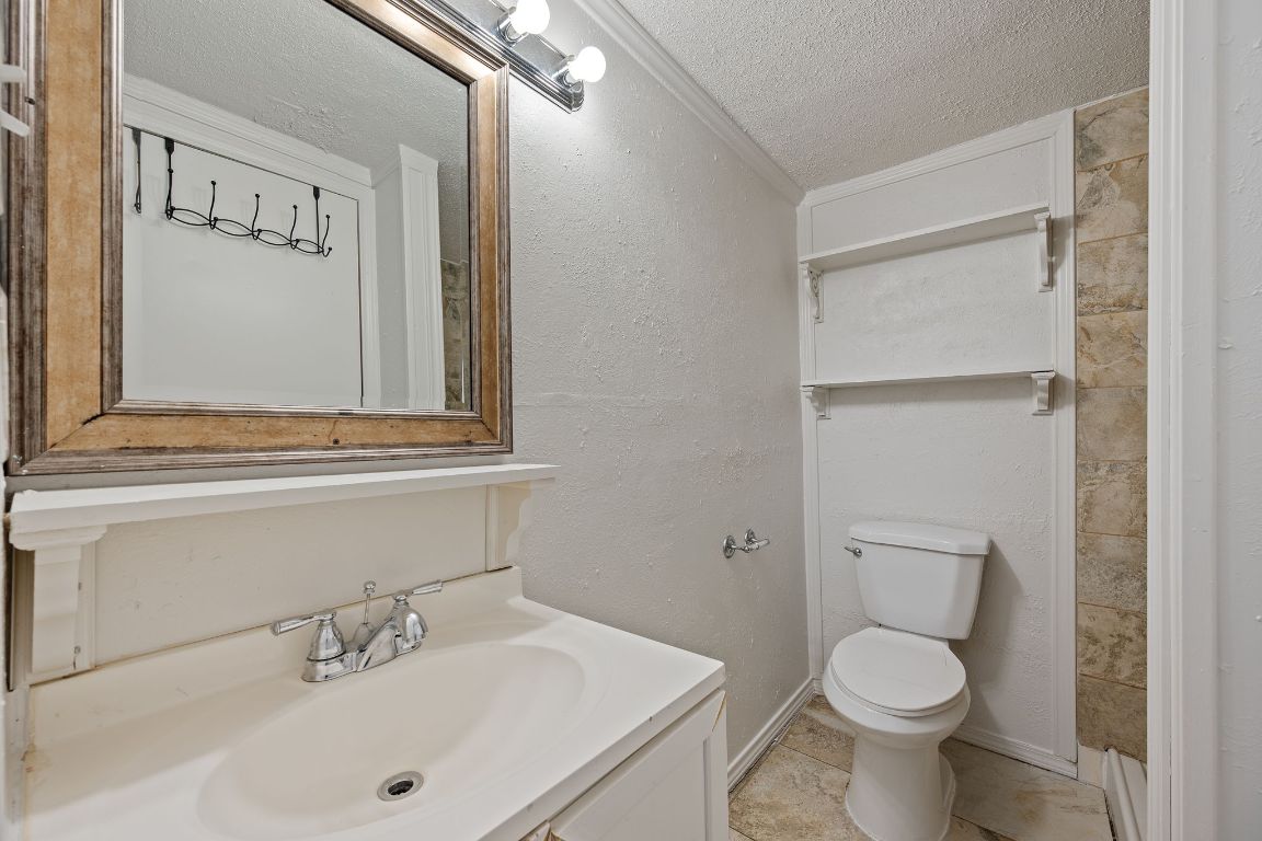 303 Irma Drive, Unit A Austin, TX 78752 - Photo 10 of 35 Bathroom featuring a textured ceiling, vanity, crown molding, and light tile patterned flooring