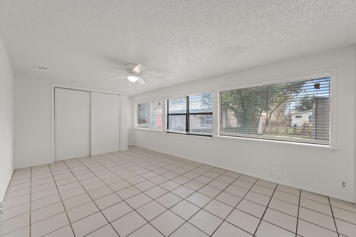 303 Irma Drive, Unit A Austin, TX 78752 - Photo 12 of 35 Unfurnished bedroom featuring a closet, a textured ceiling, ceiling fan, and light tile patterned floors