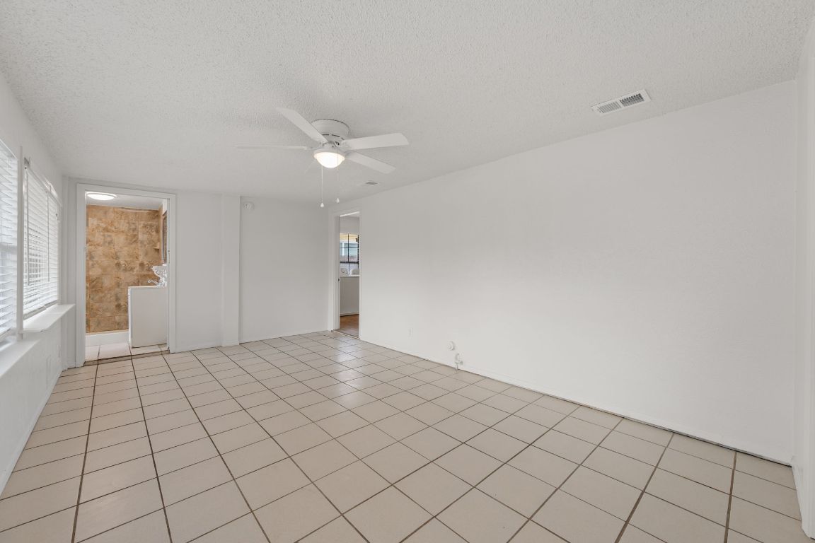 303 Irma Drive, Unit A Austin, TX 78752 - Photo 13 of 35 Bedroom featuring a textured ceiling, light tile patterned floors, and a ceiling fan