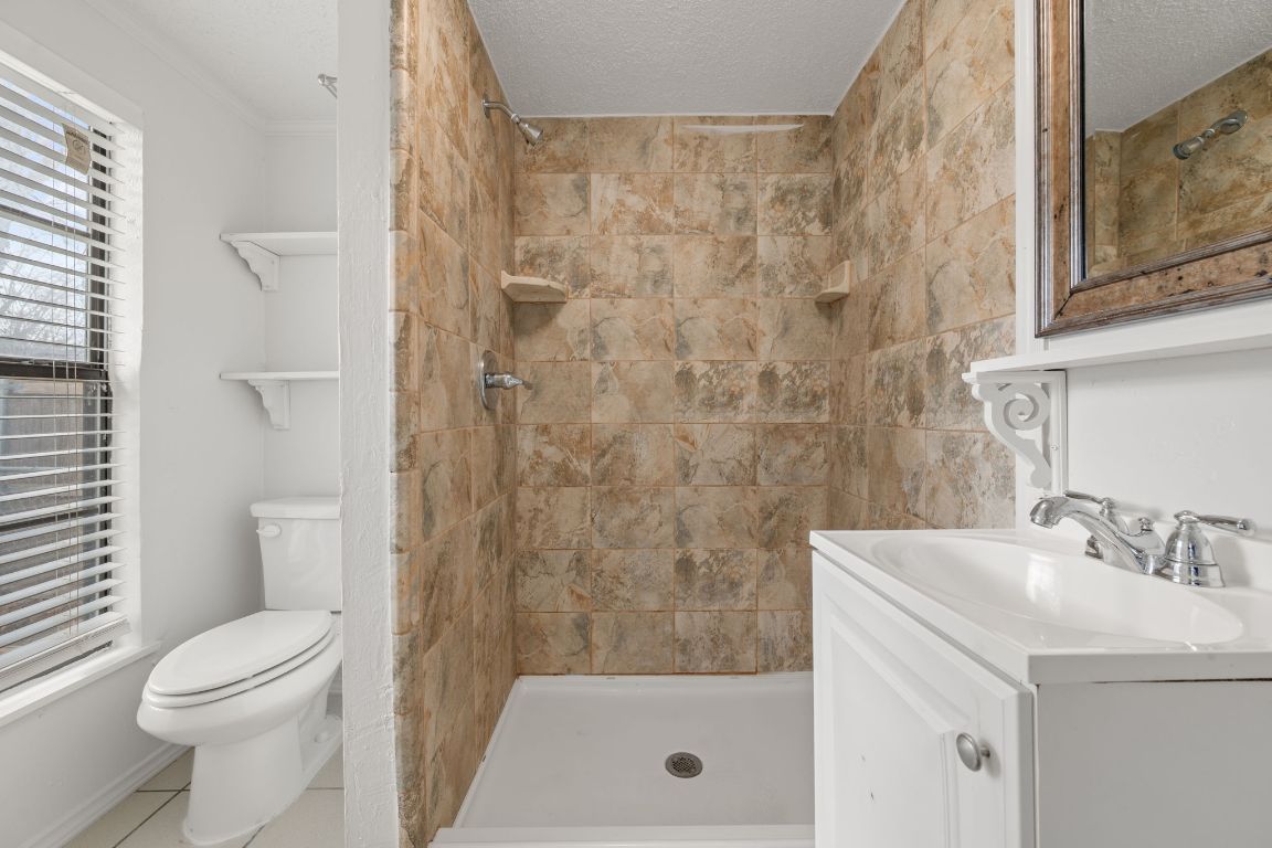 303 Irma Drive, Unit A Austin, TX 78752 - Photo 14 of 35 Bathroom with vanity, a stall shower, a textured ceiling, and tile patterned flooring