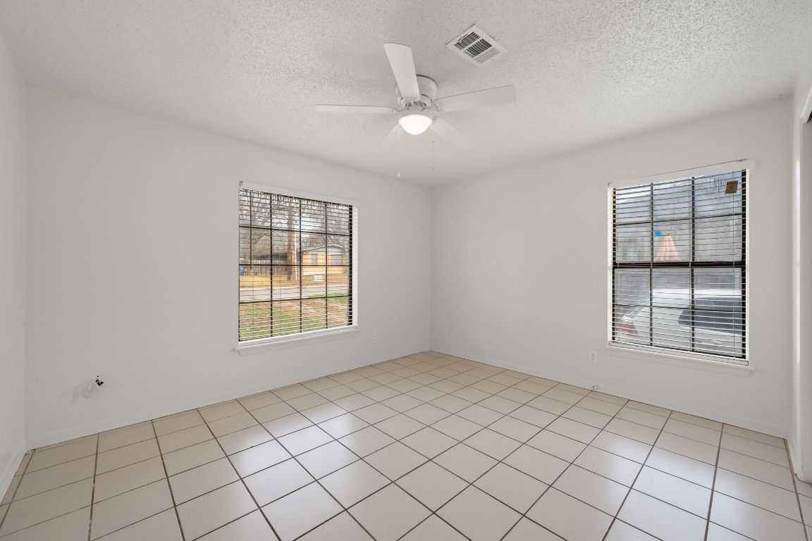 303 Irma Drive, Unit A Austin, TX 78752 - Photo 15 of 35 Spare room featuring a ceiling fan, a textured ceiling, and light tile patterned floors