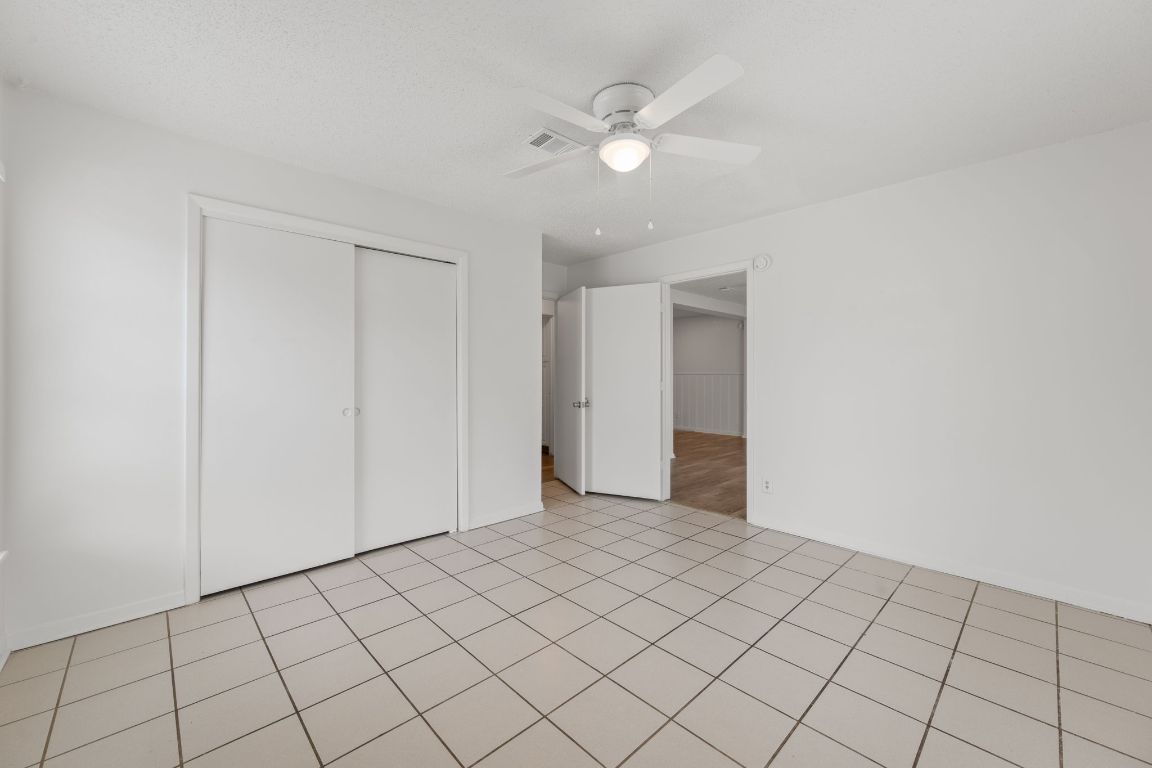 303 Irma Drive, Unit A Austin, TX 78752 - Photo 16 of 35 Unfurnished bedroom with a closet, a ceiling fan, and light tile patterned floors