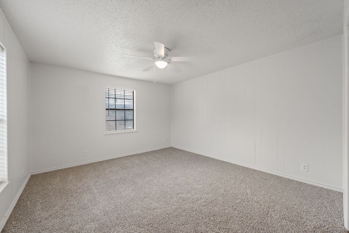 303 Irma Drive, Unit A Austin, TX 78752 - Photo 19 of 35 Empty room featuring light colored carpet, a textured ceiling, and ceiling fan