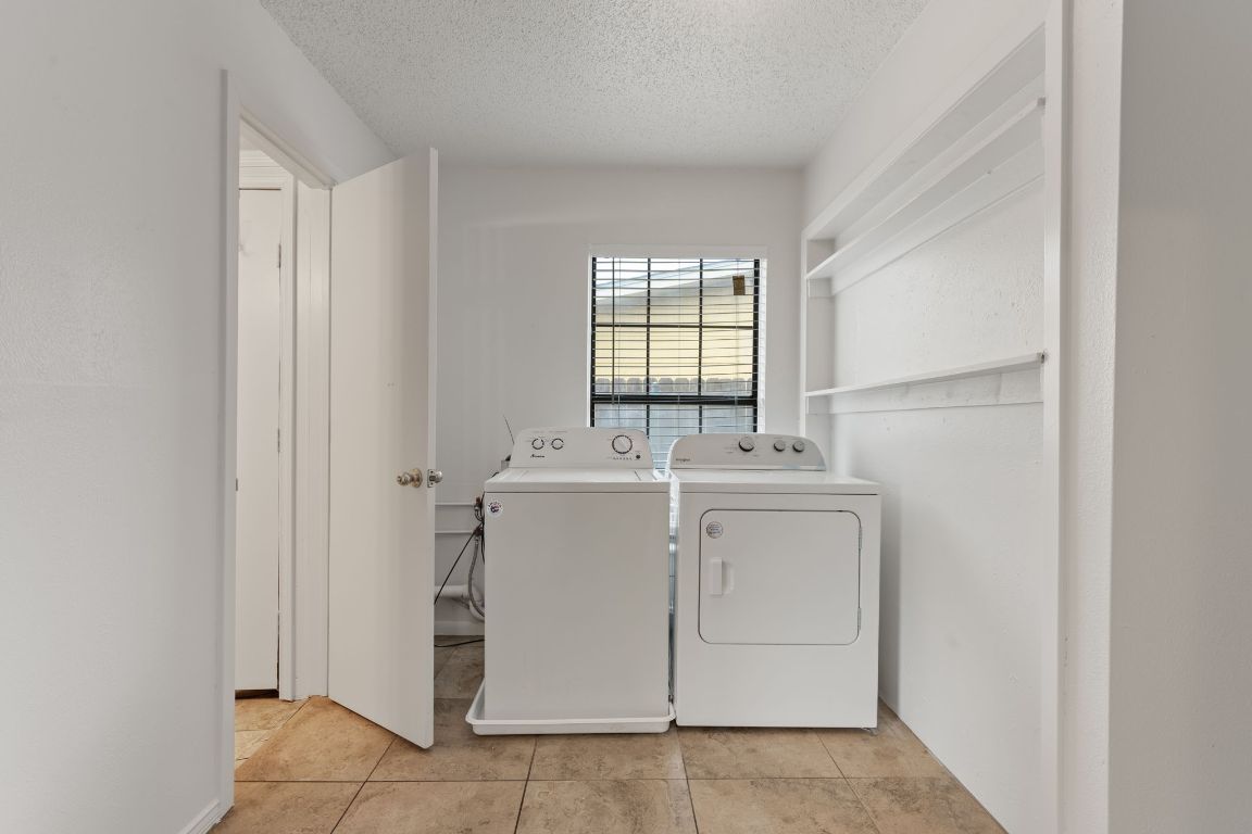 303 Irma Drive, Unit A Austin, TX 78752 - Photo 22 of 35 Laundry room featuring washer and clothes dryer, a textured ceiling, and light tile patterned floors