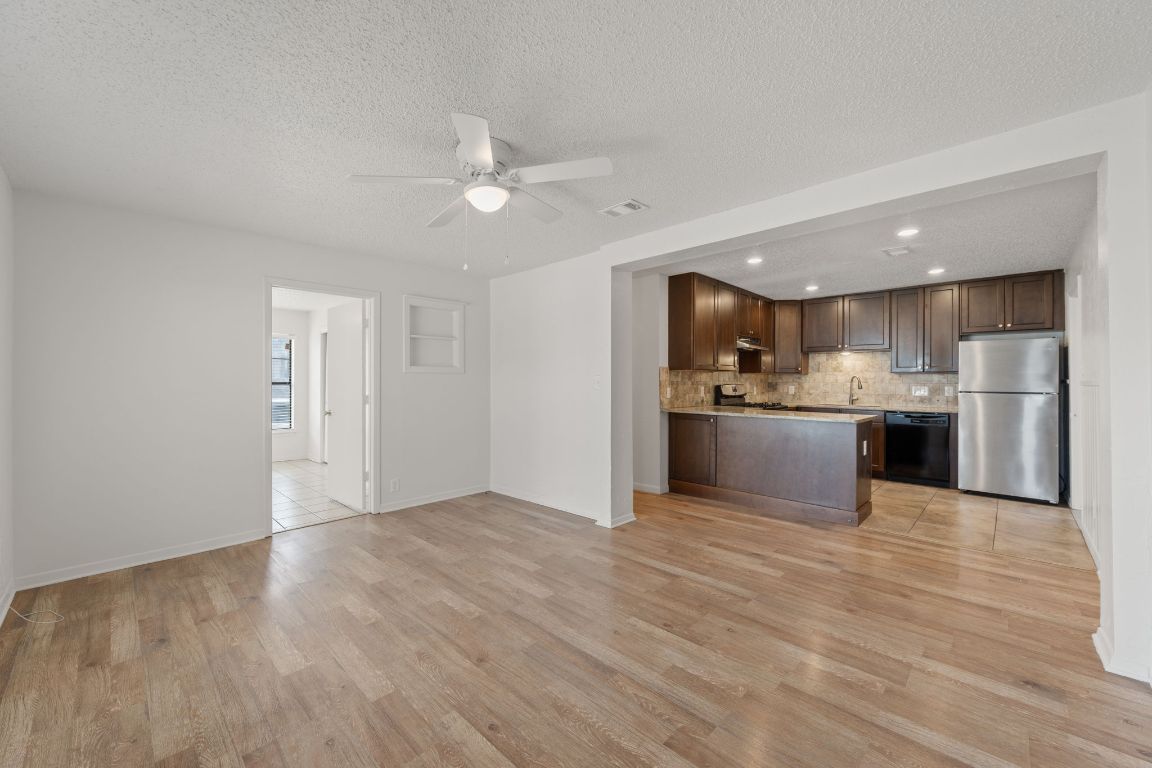303 Irma Drive, Unit A Austin, TX 78752 - Photo 34 of 35 Kitchen featuring open floor plan, dark brown cabinets, freestanding refrigerator, a peninsula, and decorative backsplash