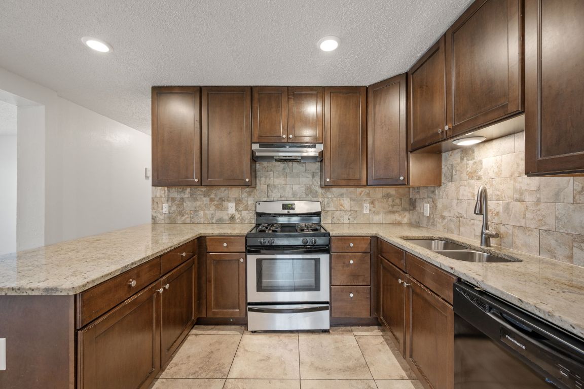 303 Irma Drive, Unit A Austin, TX 78752 - Photo 6 of 35 Kitchen with stainless steel range with gas stovetop, light stone countertops, dishwasher, recessed lighting, and dark brown cabinetry
