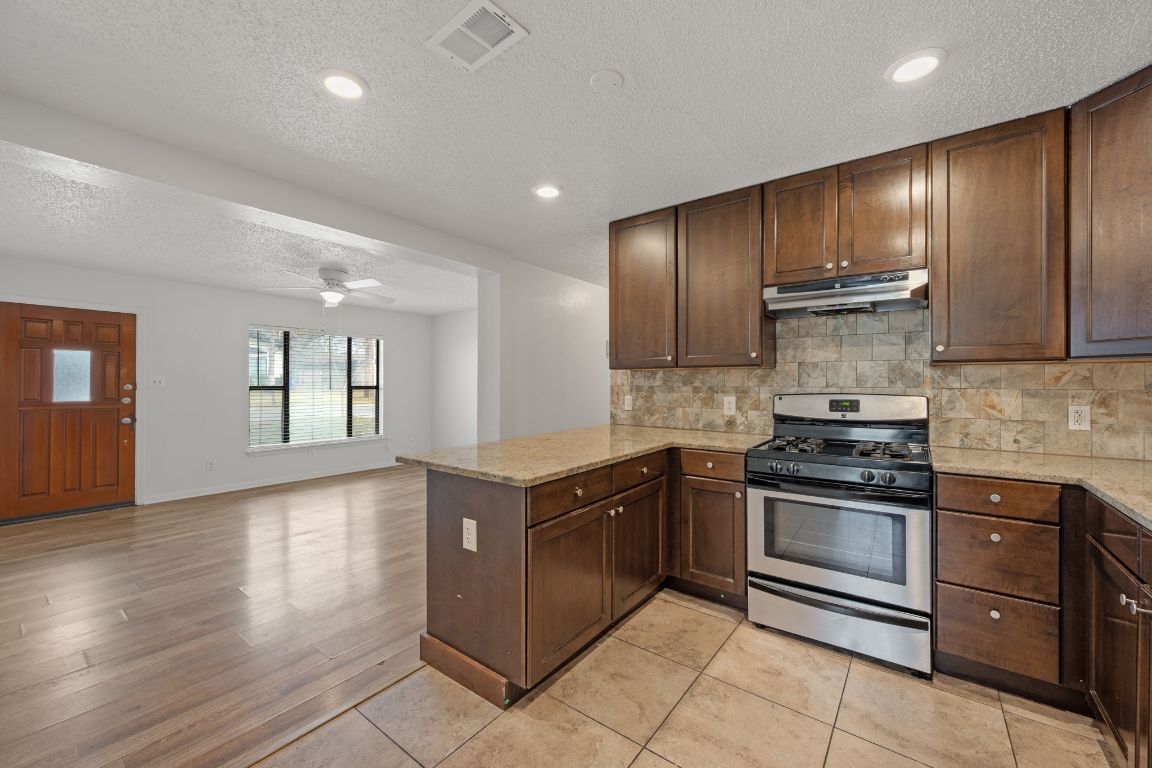 303 Irma Drive, Unit A Austin, TX 78752 - Photo 7 of 35 Kitchen featuring stainless steel gas stove, dark brown cabinetry, light stone countertops, a textured ceiling, and recessed lighting