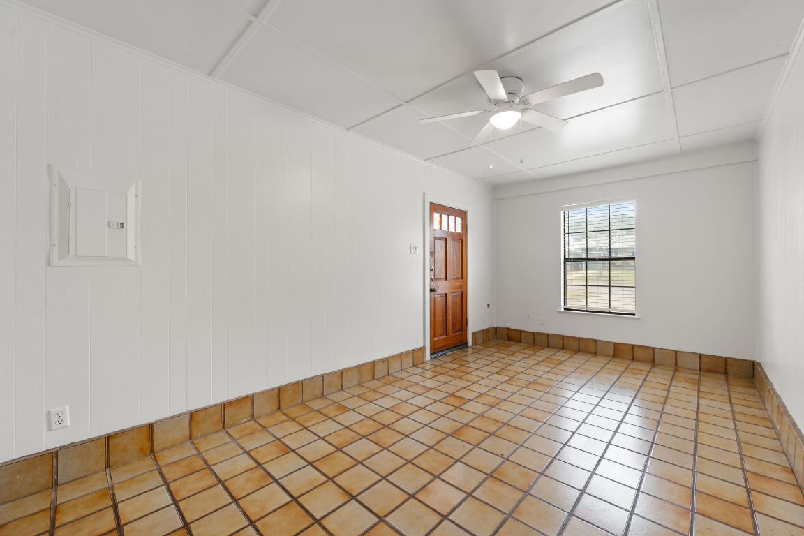303 Irma Drive, Unit A Austin, TX 78752 - Photo 8 of 35 Unfurnished room featuring electric panel, ceiling fan, tile patterned flooring, and wood walls