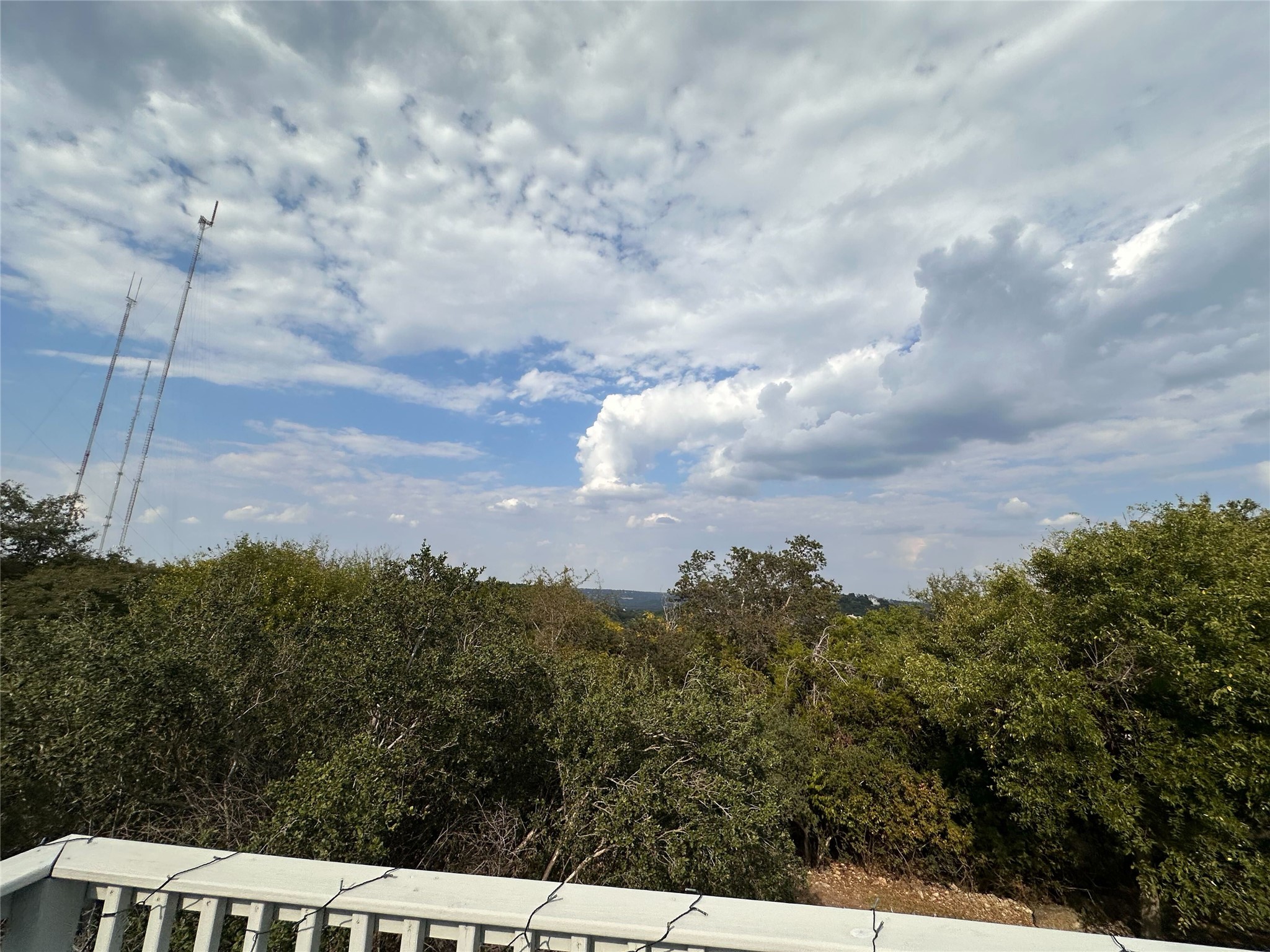 1302 Ridgecrest Drive Austin, TX 78746 - Photo 17 of 19 Lush tree canopies stretch across the horizon beneath a vast, cloud-filled sky.
