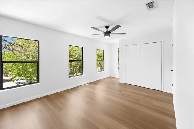 a view of empty room with wooden floor and fan