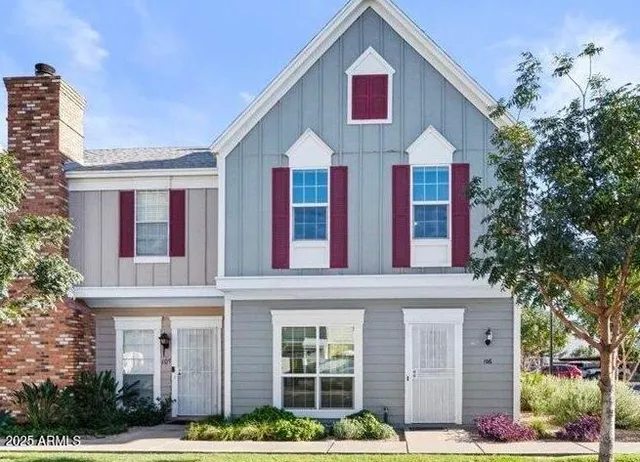a view of a white house with large windows and a table and chairs