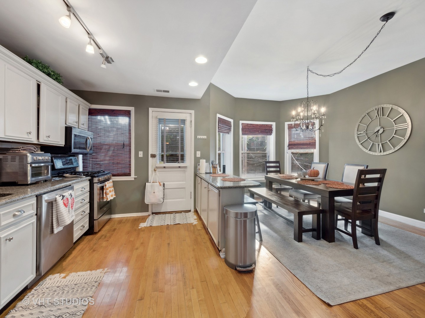 1023 West Dakin Street, Unit 2W Chicago, IL 60613 - Photo 3 of 10 a kitchen with stainless steel appliances granite countertop a stove top oven a sink dishwasher a dining table and chairs with wooden floor