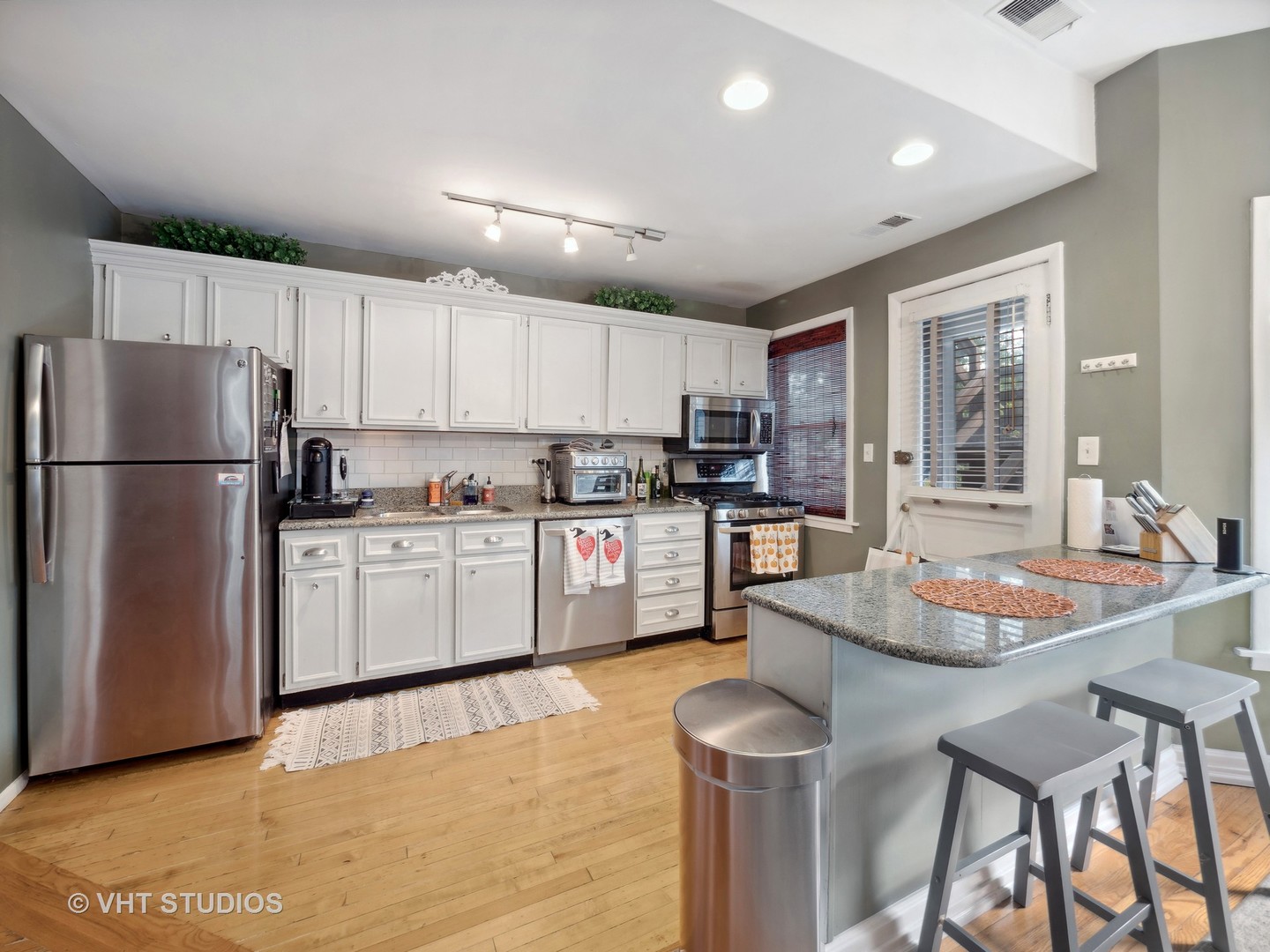 1023 West Dakin Street, Unit 2W Chicago, IL 60613 - Photo 4 of 10 a kitchen with granite countertop a refrigerator a stove a sink a dining table and chairs