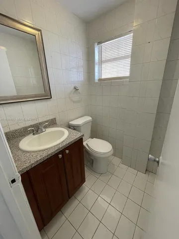 a bathroom with a granite countertop sink toilet and mirror