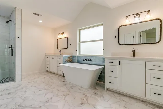a spacious bathroom with a double vanity sink mirror and bathtub