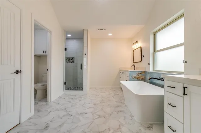 a bathroom with a tub a sink a mirror and a shower