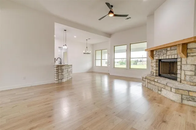 a view of an empty room with wooden floor fireplace and a window