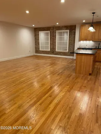 a view of a livingroom with wooden floor and a kitchen
