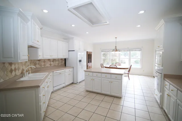 a large kitchen with granite countertop white cabinets and white appliances