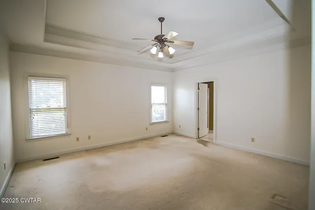 an empty room with chandelier fan and windows
