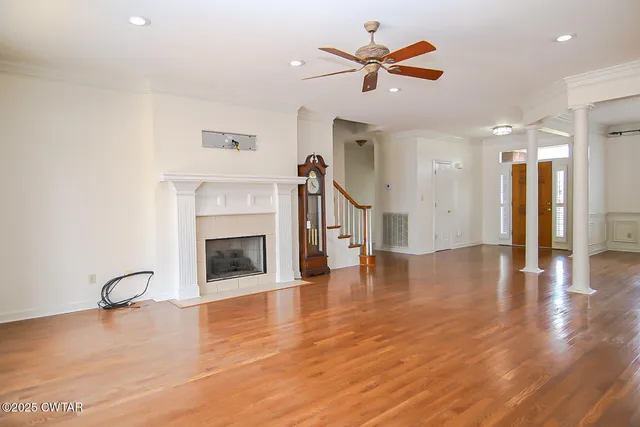 a view of a livingroom with a fireplace a ceiling fan and kitchen floor