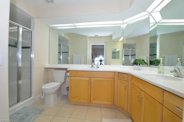 a spacious bathroom with a granite countertop sink a toilet a mirror and shower