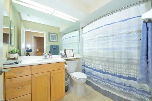 a bathroom with a granite countertop sink a toilet a mirror and shower