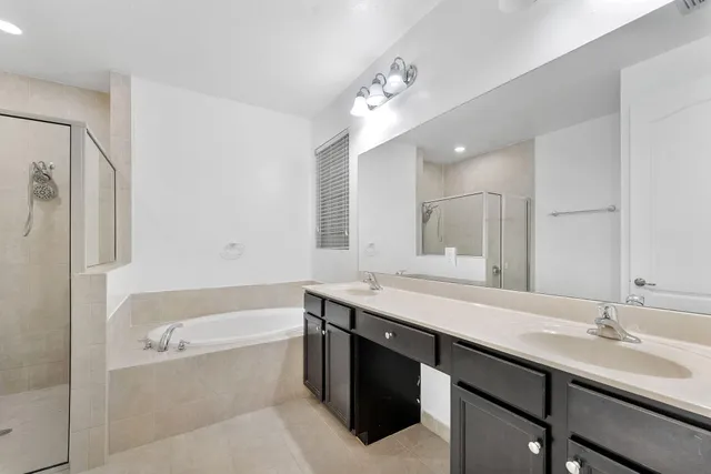 a bathroom with a granite countertop bathtub sink double and mirror