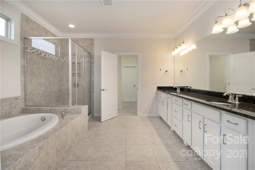 7007 Fallondale Road Waxhaw, NC 28173 - Photo 10 of 24 a bathroom with a double vanity sink a large mirror and a bathtub